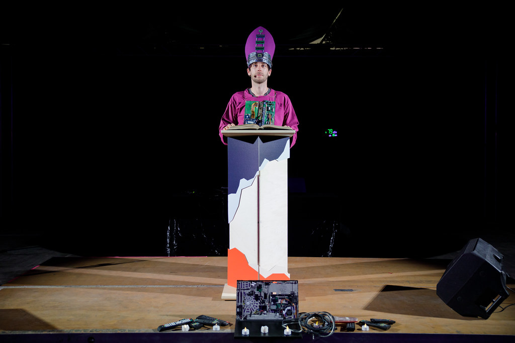 Un genre de prêtre devant un pupitre et des objets démontés